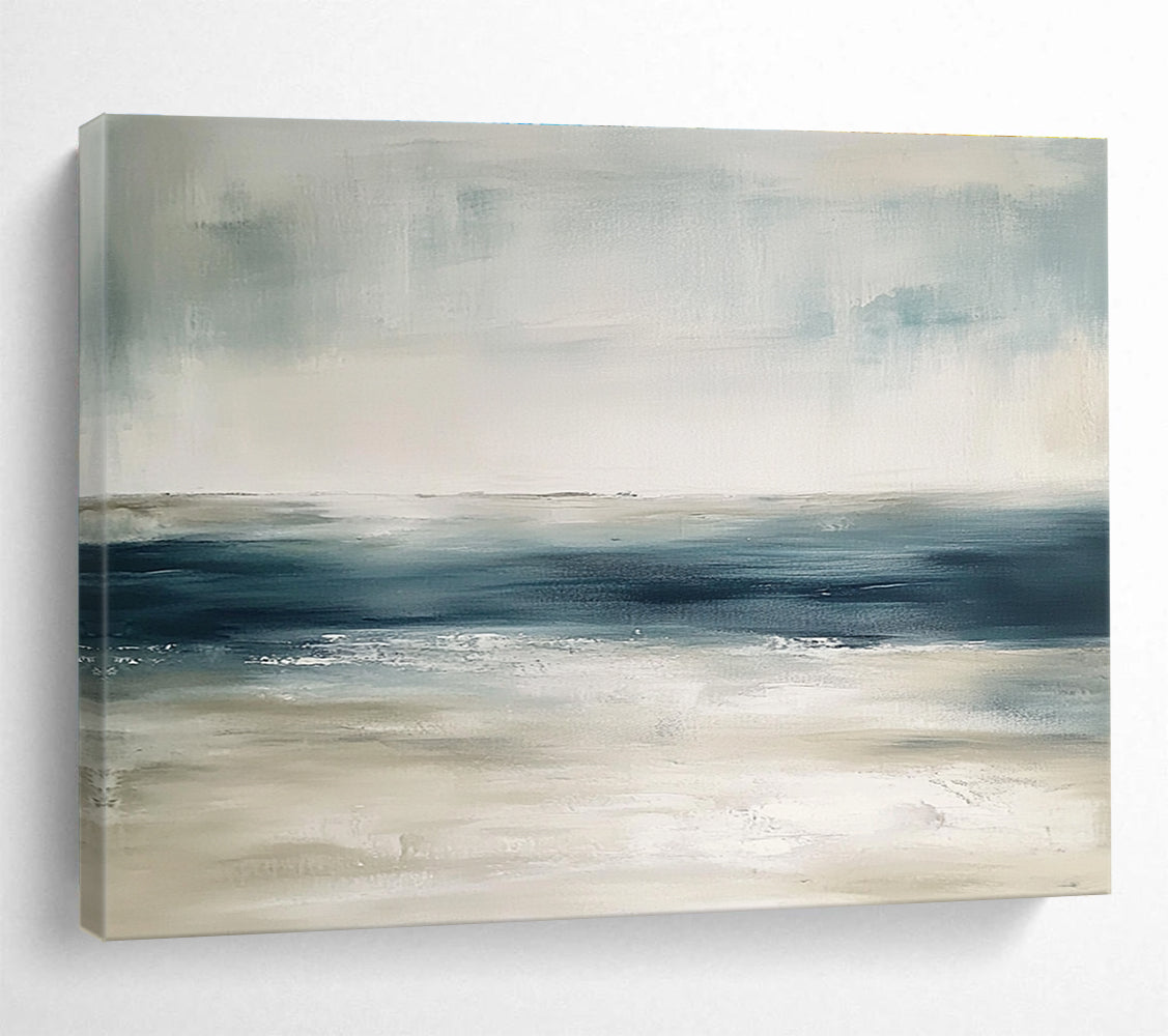 Large abstract painting featuring tranquil blue and gray tones with sandy beige hints soft brushstrokes evoke a serene ocean landscape.SC277