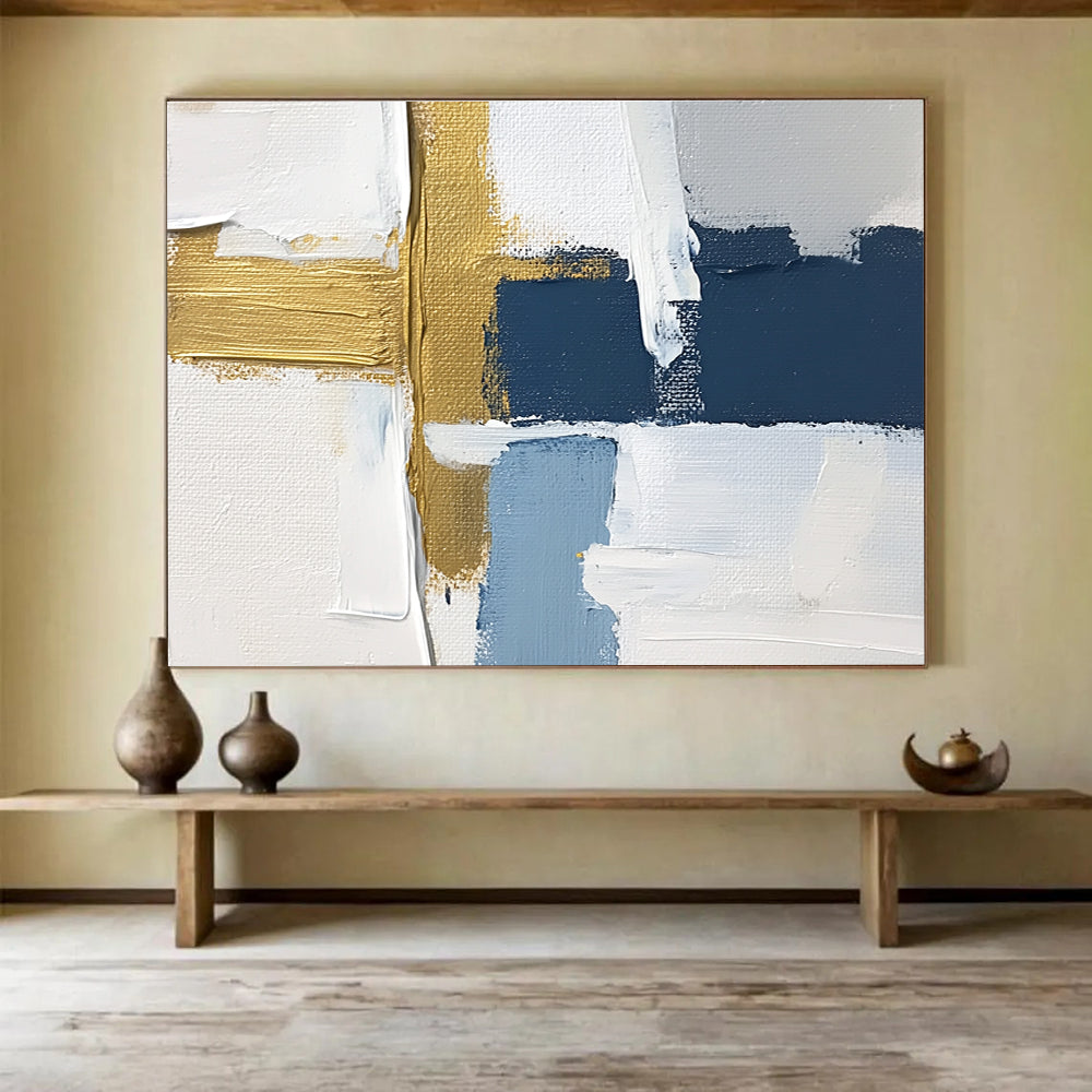Large abstract painting with white blue and gold blocks featuring brushstrokes and texture showcasing a golden cross for depth in a serene atmosphere.SC267