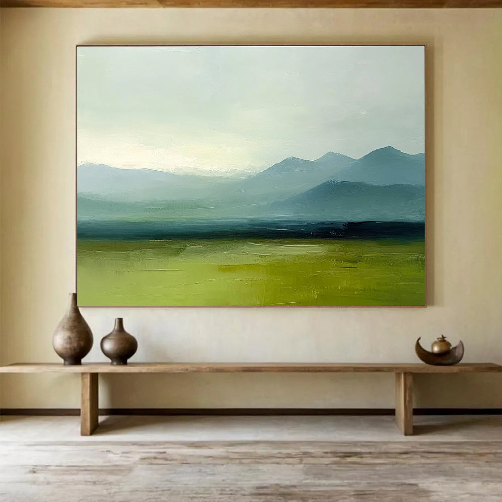 A large abstract oil painting depicting grassy plains and distant mountains in a minimalist style with a green and blue palette under a grey sky.SC409