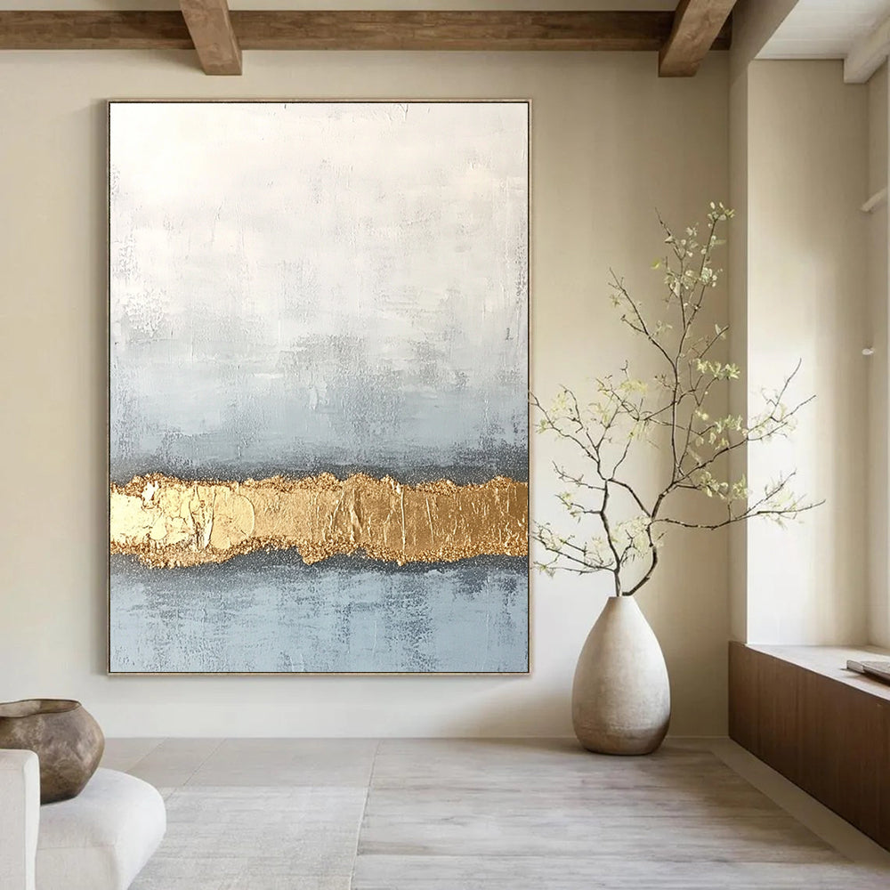 Large abstract painting with textured surface in soft gray and pale blue featuring a golden glitter line at the bottom.STSC735