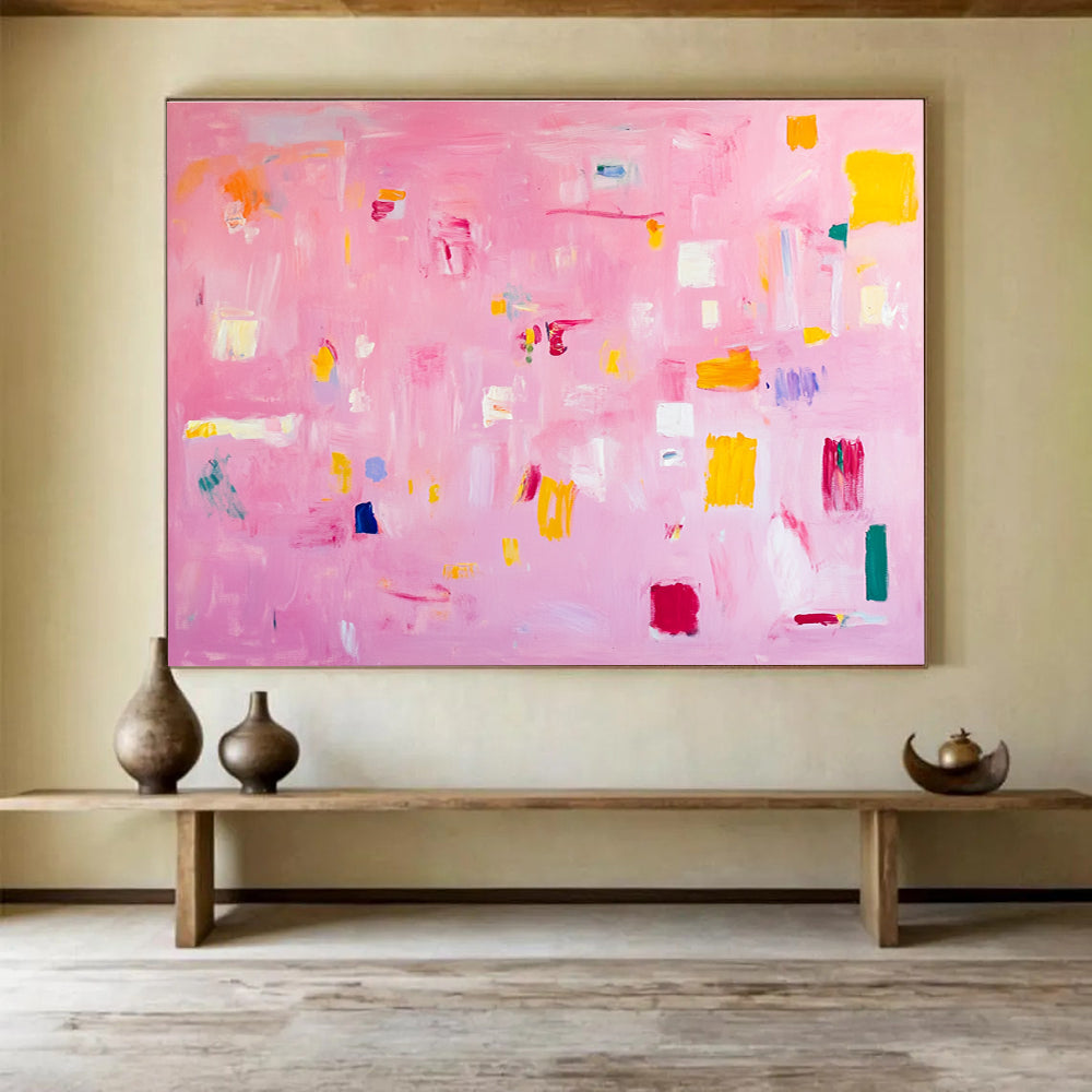 A large abstract painting featuring soft pink hues bright yellow blocks red lines and white squares creates a joyful warm atmosphere perfect for celebration.SC536