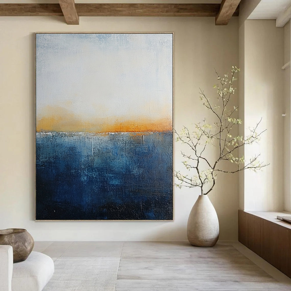 Large abstract painting with layered blue and yellow textures evokes oceanic depths at dusk with soft lighting enhancing movement and depth.STSC109