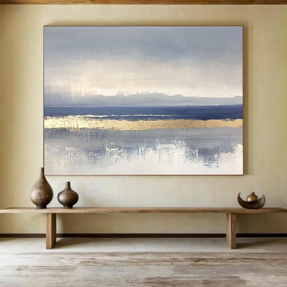 Large abstract painting featuring soft blue and gray tones with gold accents and visible brush strokes on a neutral background.SC038