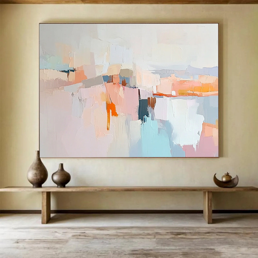 Large abstract painting in soft pastels featuring hills mountains a light grey sky peach-pink clouds and serene water for a calming effect.SC353