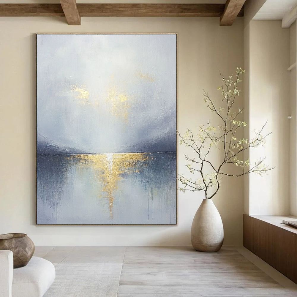 Large abstract painting featuring a grey sky clouds gold horizon and a tranquil lake in the foreground with soft muted colors.STSC289