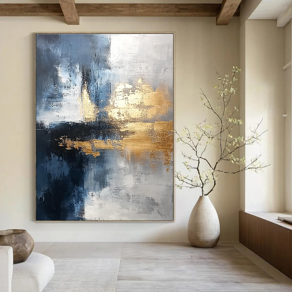 Large abstract painting blending silver and gold with gray blue tones and light brushstrokes featuring exquisite details and a unique composition for a calming atmosphere.STSC376
