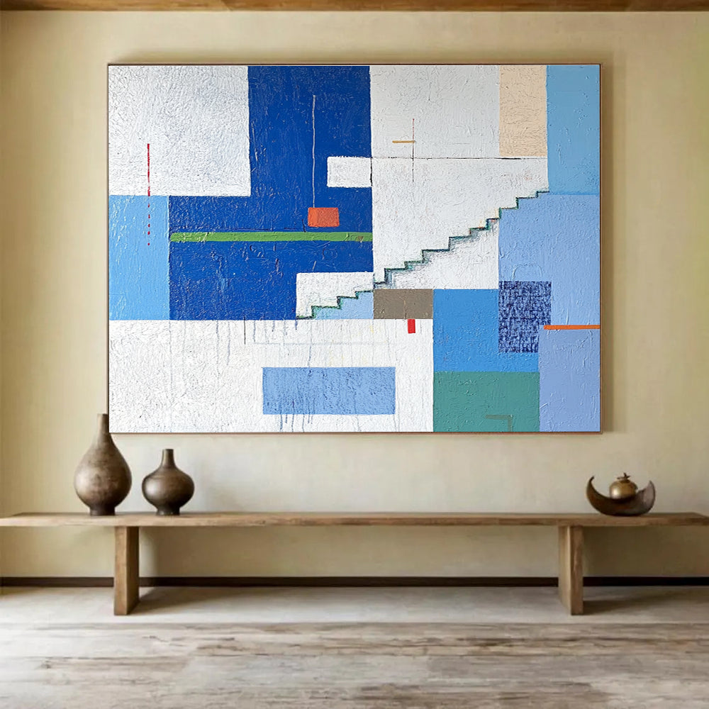 A large abstract painting of an urban landscape in blue and white tones, featuring geometric buildings with green accents, stairs, windows, and doors.SC488