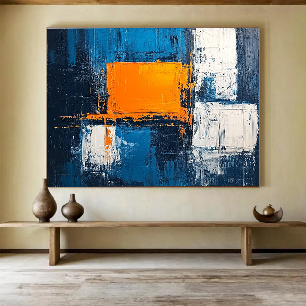 Large abstract painting featuring a textured pale blue background bold orange square white blocks and dark gray light indigo accents in acrylic.SC225