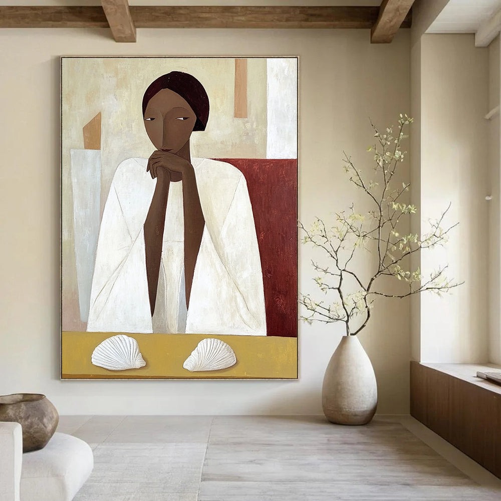 A large abstract painting featuring an African woman in a white cloak sitting on a yellow table with shells in daylight.STSC1115
