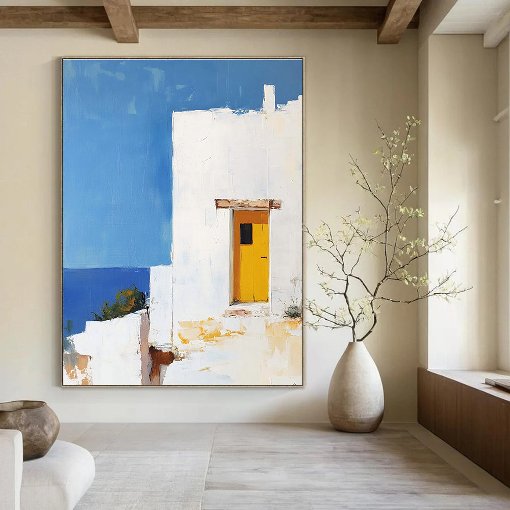 Large abstract painting featuring a white Greek house with a yellow door set against a blue sky in minimalistic style.STSC1252