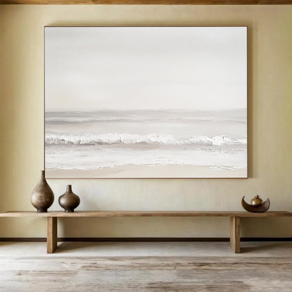 A large abstract painting of the sea featuring light gray and white tones with serene waves and a beige beach for added depth.SC502