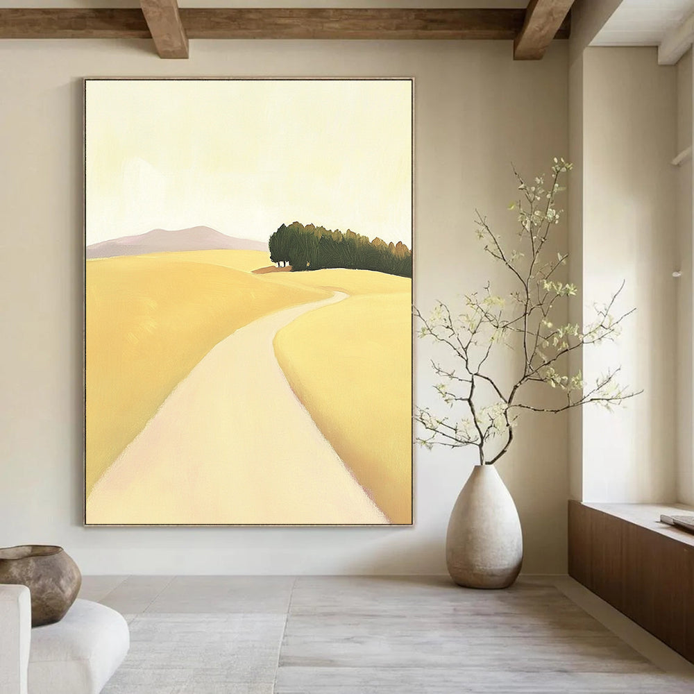 A large abstract painting depicting a minimalist road in an open field with hills and trees in soft yellow beige and green tones.STSC1167