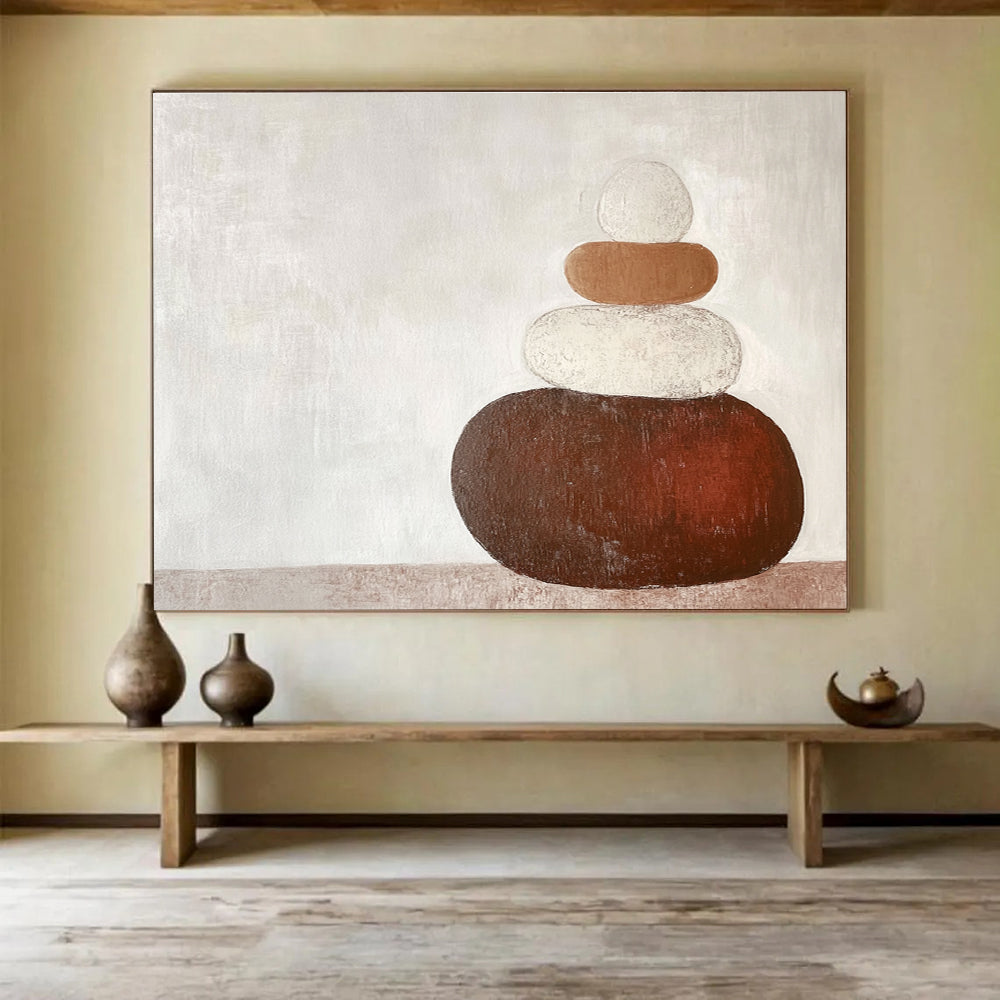 Large abstract painting in earth tones featuring three stacked rocks against a white background creating an elegant contrast.SC495