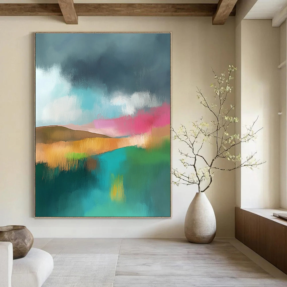 Large abstract painting featuring light teal and pink hues with a green field brown hills and a dark grey sky adorned with white clouds.STSC087