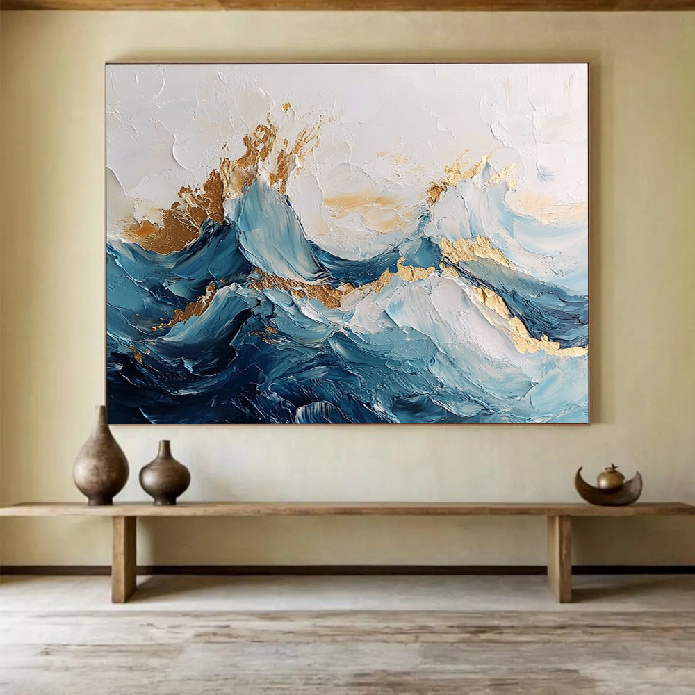 Large abstract painting of ocean waves in blue and white with gold accents featuring textured brush strokes and fluid shapes that convey movement.SC101