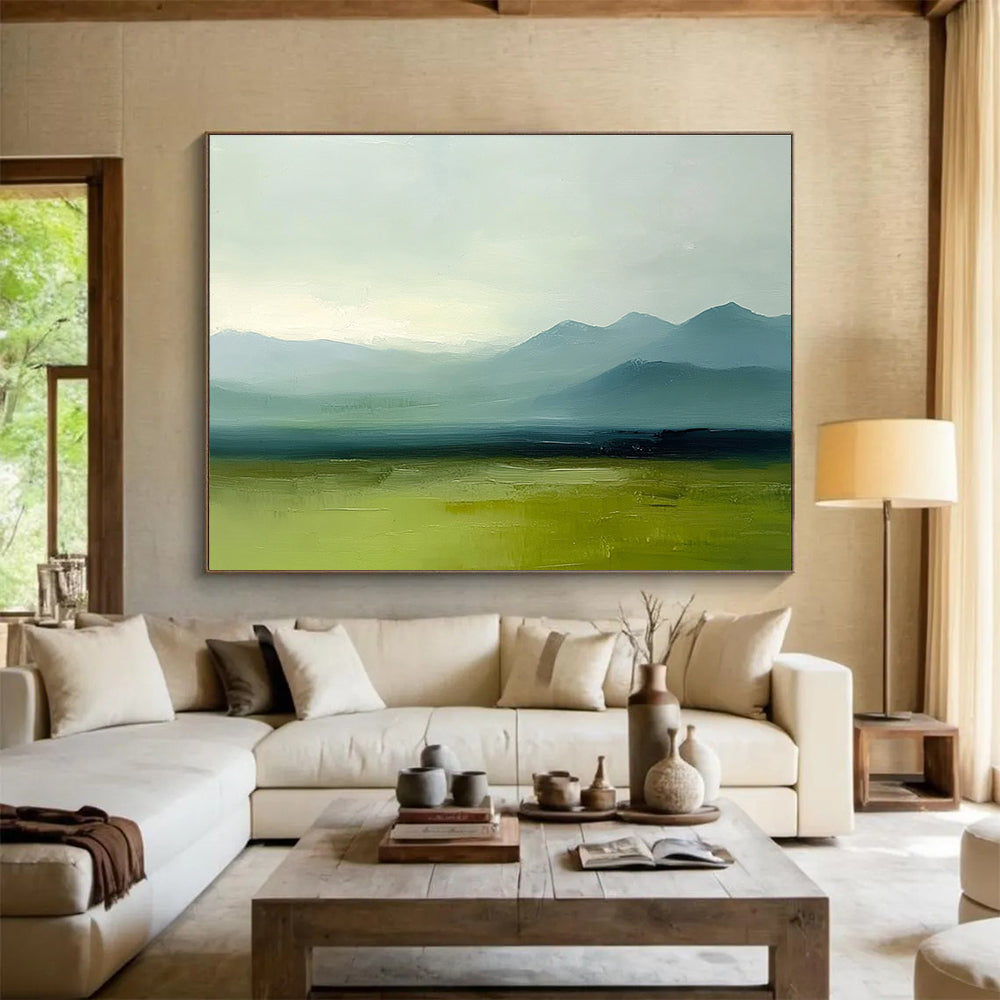 A large abstract oil painting depicting grassy plains and distant mountains in a minimalist style with a green and blue palette under a grey sky.SC409