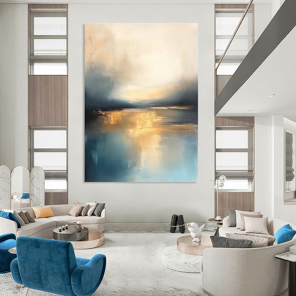 Large abstract painting featuring soft blue and gold tones with a calm sea reflections dramatic clouds and a tranquil sky.STSC103