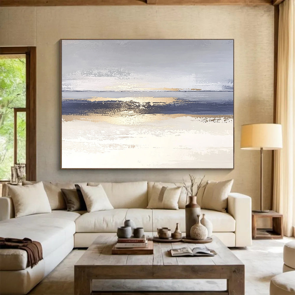 Large abstract painting with soft light blue and gray tones featuring metallic gold lines depicting water ripples on serene sand.SC007