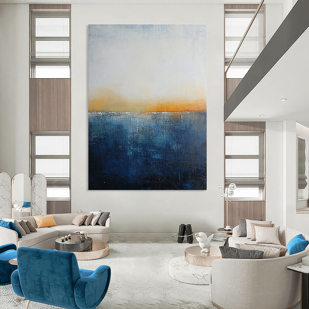 Large abstract painting with layered blue and yellow textures evokes oceanic depths at dusk with soft lighting enhancing movement and depth.STSC109