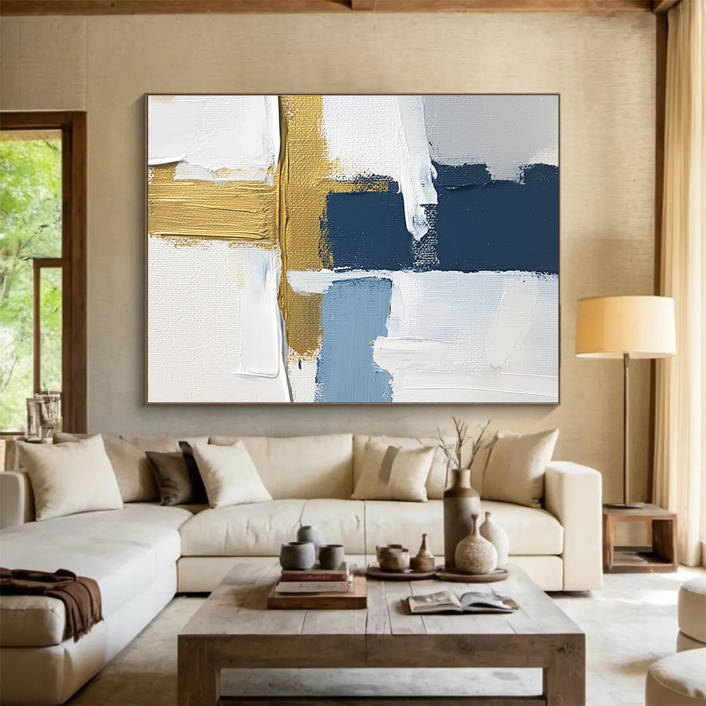 Large abstract painting with white blue and gold blocks featuring brushstrokes and texture showcasing a golden cross for depth in a serene atmosphere.SC267