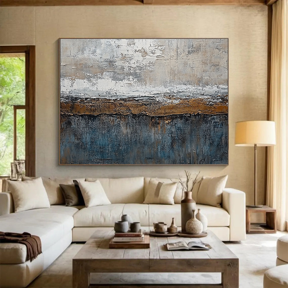 Large abstract painting features textured layers of grey, brown, blue, and bronze with painterly strokes and metal accents creating an artistic landscape.SC174