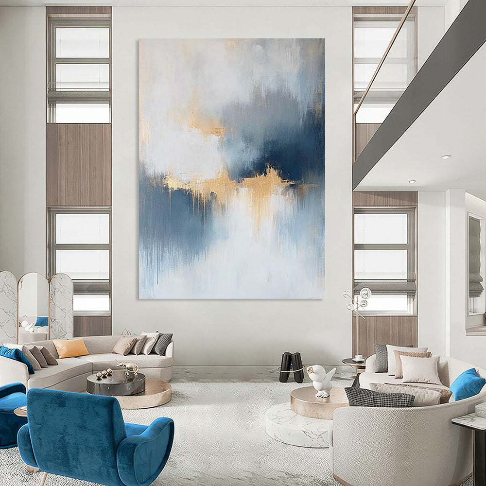 Large abstract painting featuring atmospheric clouds in soft blue gray and white tones with gold and silver accents and delicate textures.STSC386
