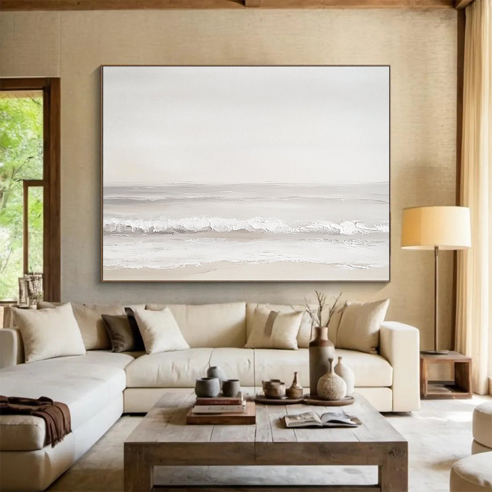 A large abstract painting of the sea featuring light gray and white tones with serene waves and a beige beach for added depth.SC502