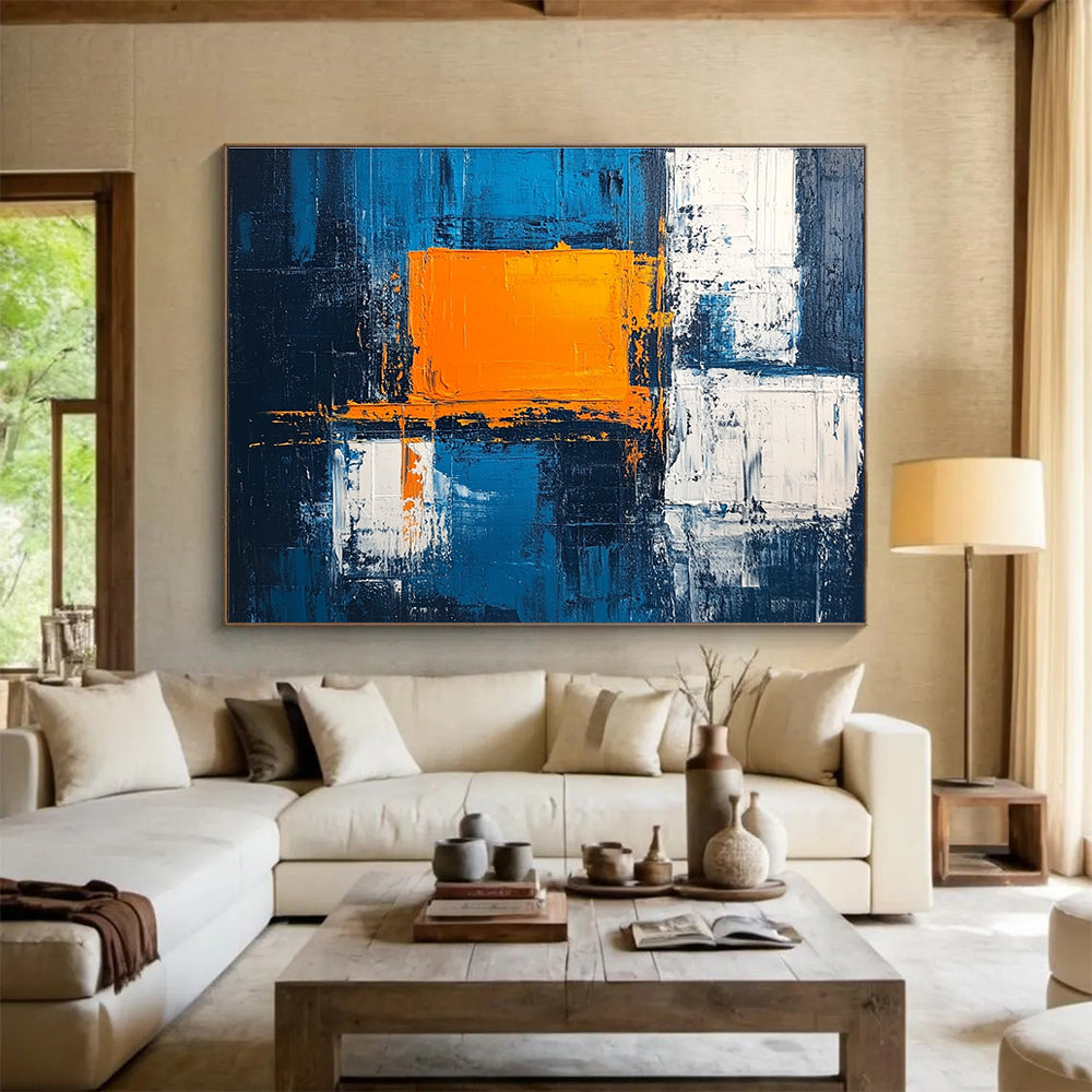 Large abstract painting featuring a textured pale blue background bold orange square white blocks and dark gray light indigo accents in acrylic.SC225