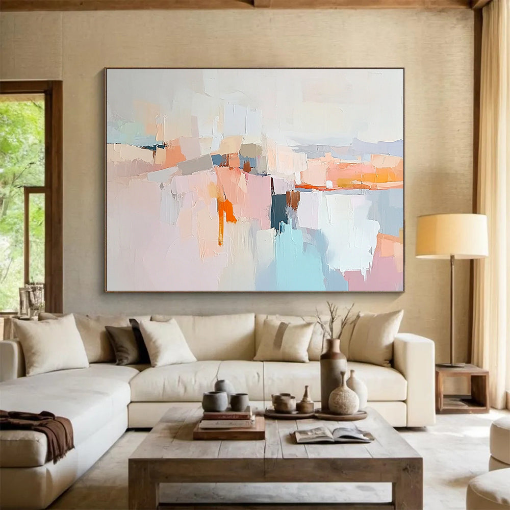 Large abstract painting in soft pastels featuring hills mountains a light grey sky peach-pink clouds and serene water for a calming effect.SC353