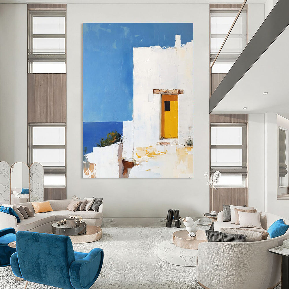 Large abstract painting featuring a white Greek house with a yellow door set against a blue sky in minimalistic style.STSC1252