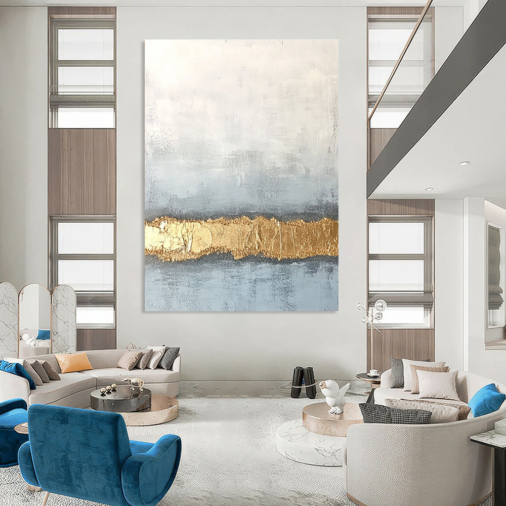 Large abstract painting with textured surface in soft gray and pale blue featuring a golden glitter line at the bottom.STSC735