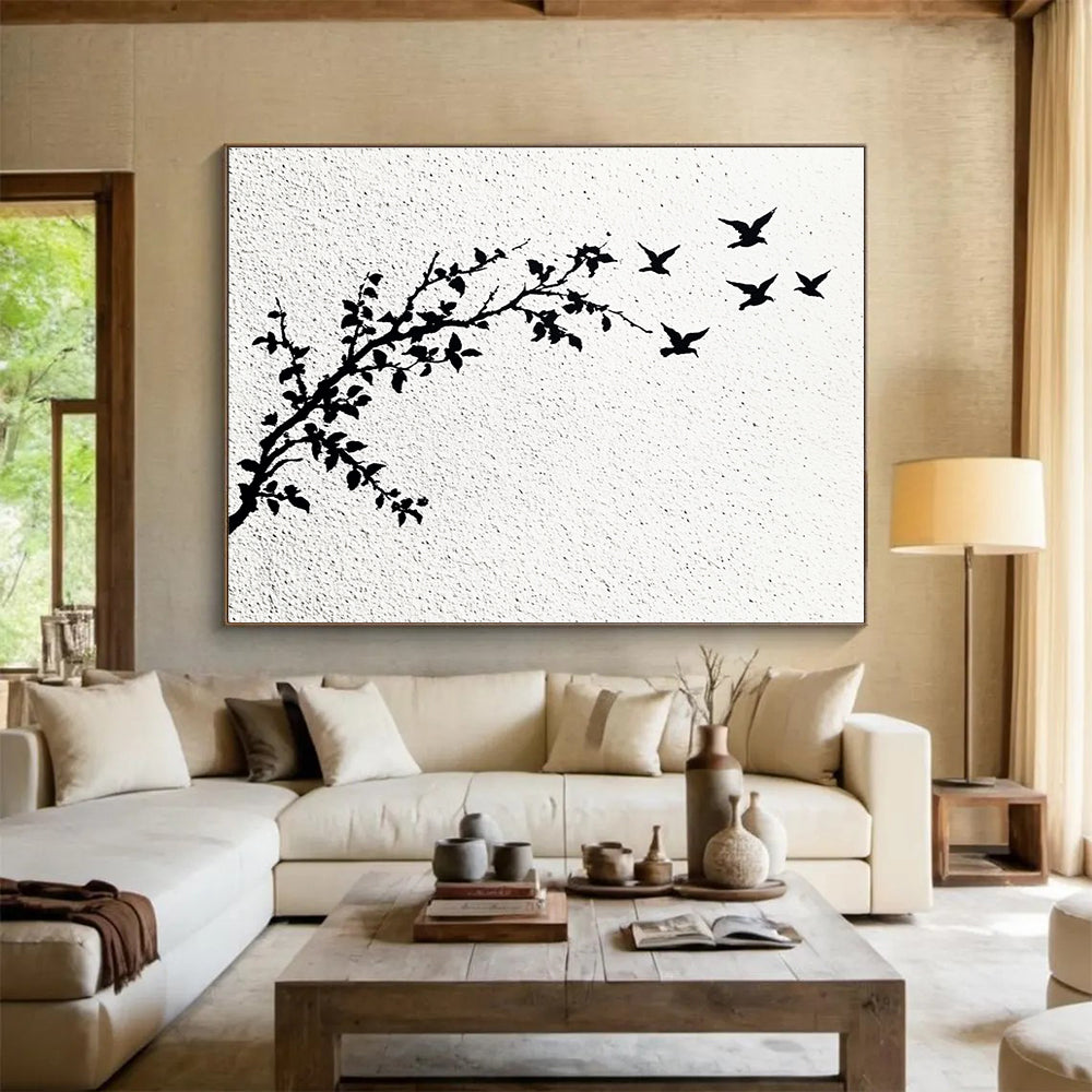 A large abstract painting featuring delicate branches with leaves and black and white flying birds against an off-white wall.SC434