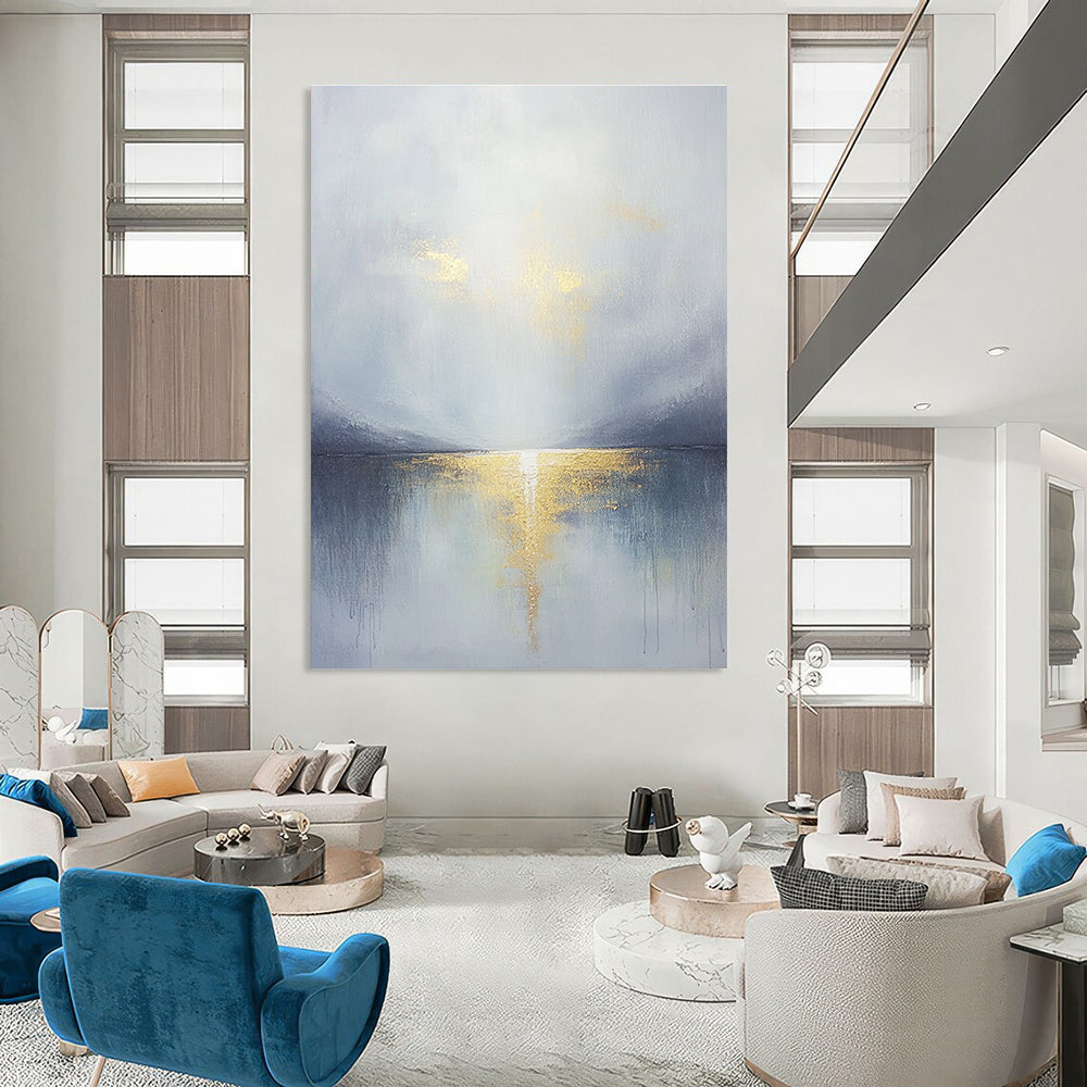 Large abstract painting featuring a grey sky clouds gold horizon and a tranquil lake in the foreground with soft muted colors.STSC289