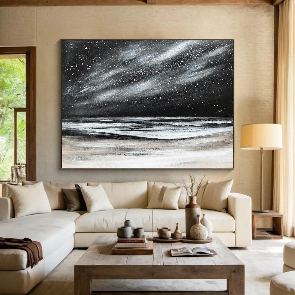 Large abstract painting depicting a dark stormy sky with stars and snow on the beach in black and white colors.SC295