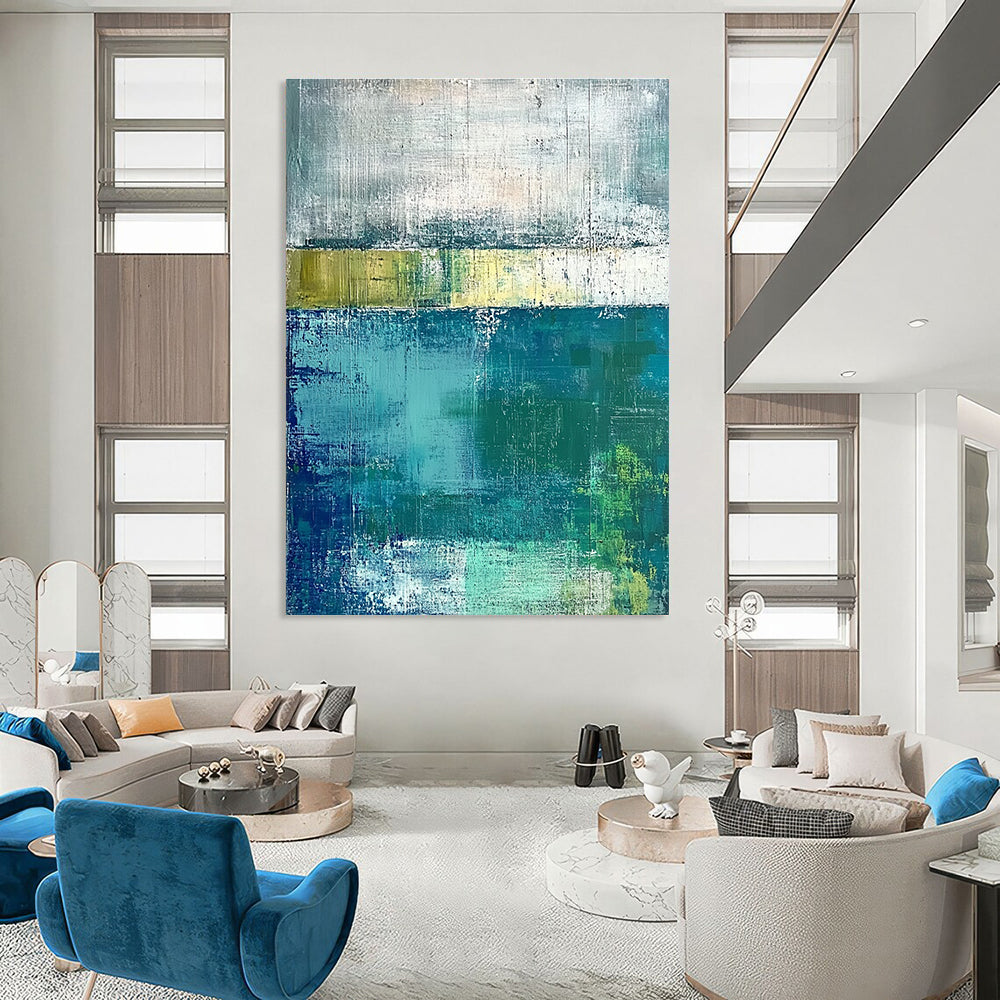 Large abstract painting with green and blue tones on a gray background evokes a serene water's edge mood with textured surfaces.STSC420