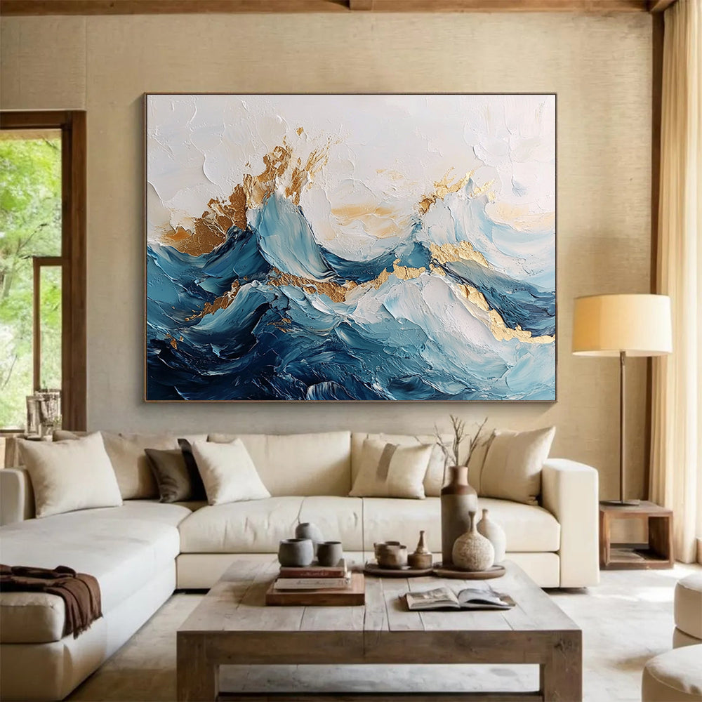 Large abstract painting of ocean waves in blue and white with gold accents featuring textured brush strokes and fluid shapes that convey movement.SC101