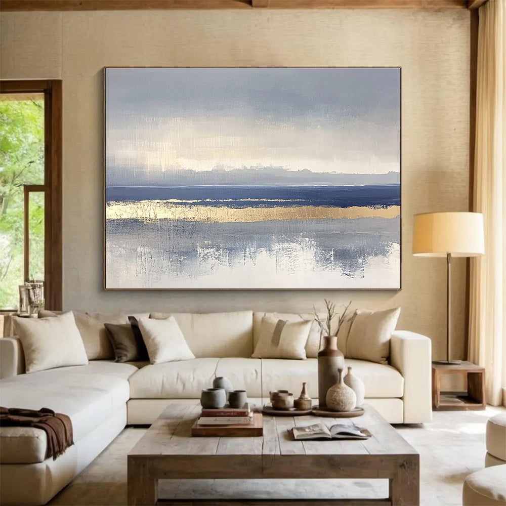 Large abstract painting featuring soft blue and gray tones with gold accents and visible brush strokes on a neutral background.SC038