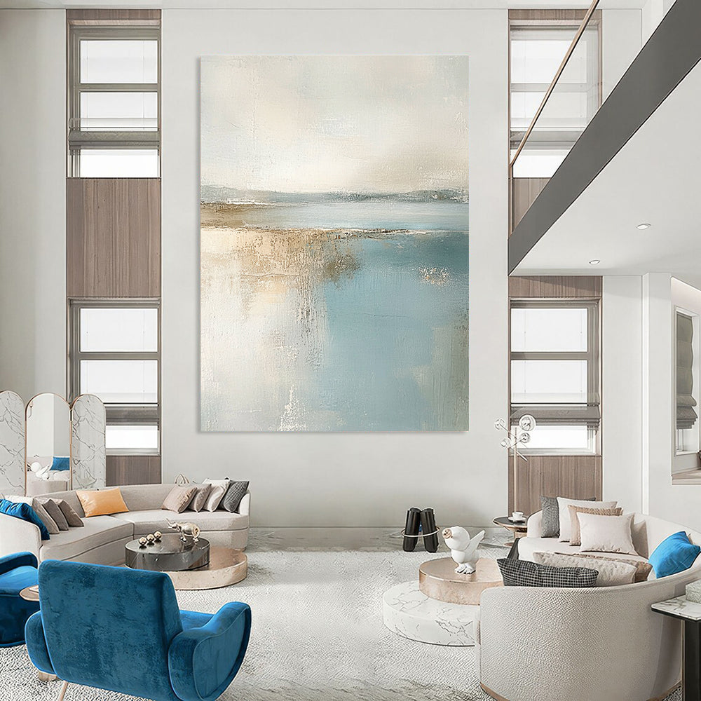 Large abstract painting featuring muted pastel colors of beige and light blue creating a calming beach landscape in neutral tones.STSC017