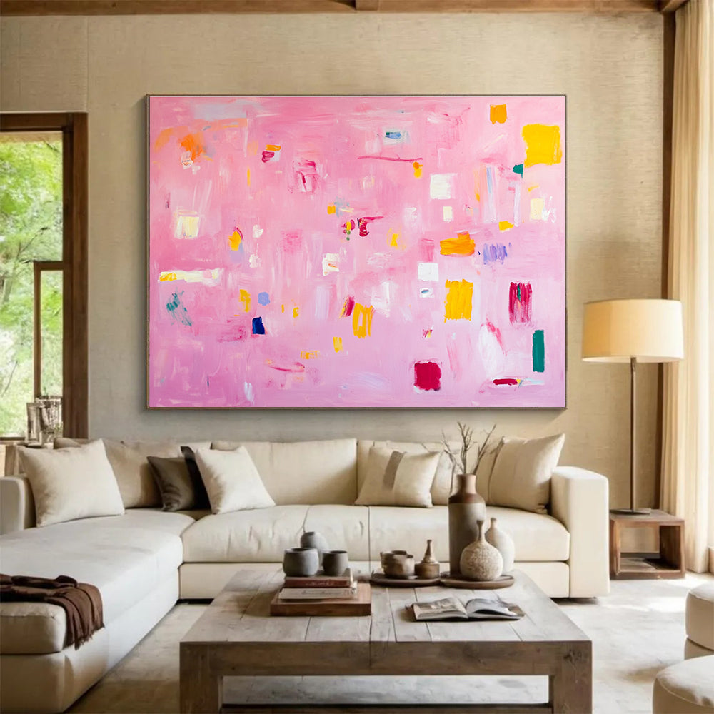 A large abstract painting featuring soft pink hues bright yellow blocks red lines and white squares creates a joyful warm atmosphere perfect for celebration.SC536