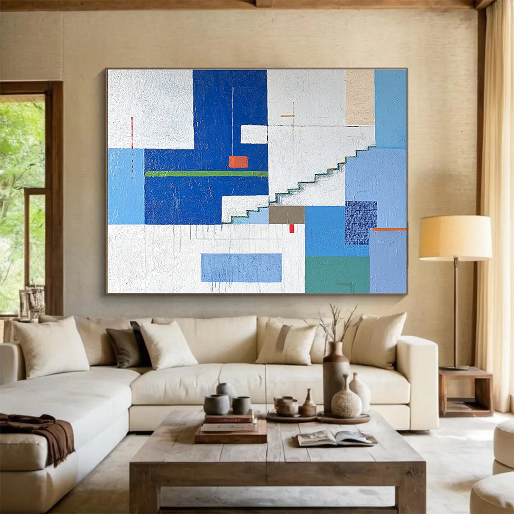 A large abstract painting of an urban landscape in blue and white tones, featuring geometric buildings with green accents, stairs, windows, and doors.SC488