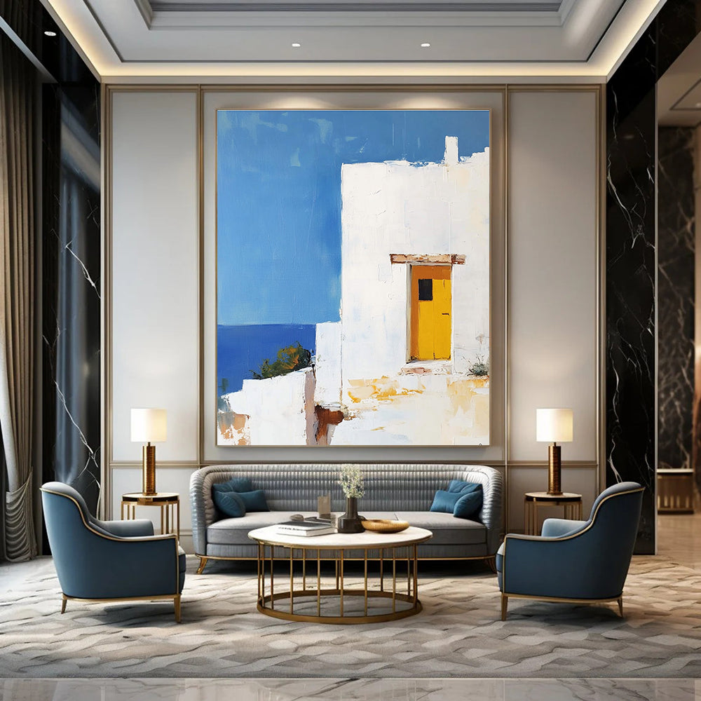 Large abstract painting featuring a white Greek house with a yellow door set against a blue sky in minimalistic style.STSC1252