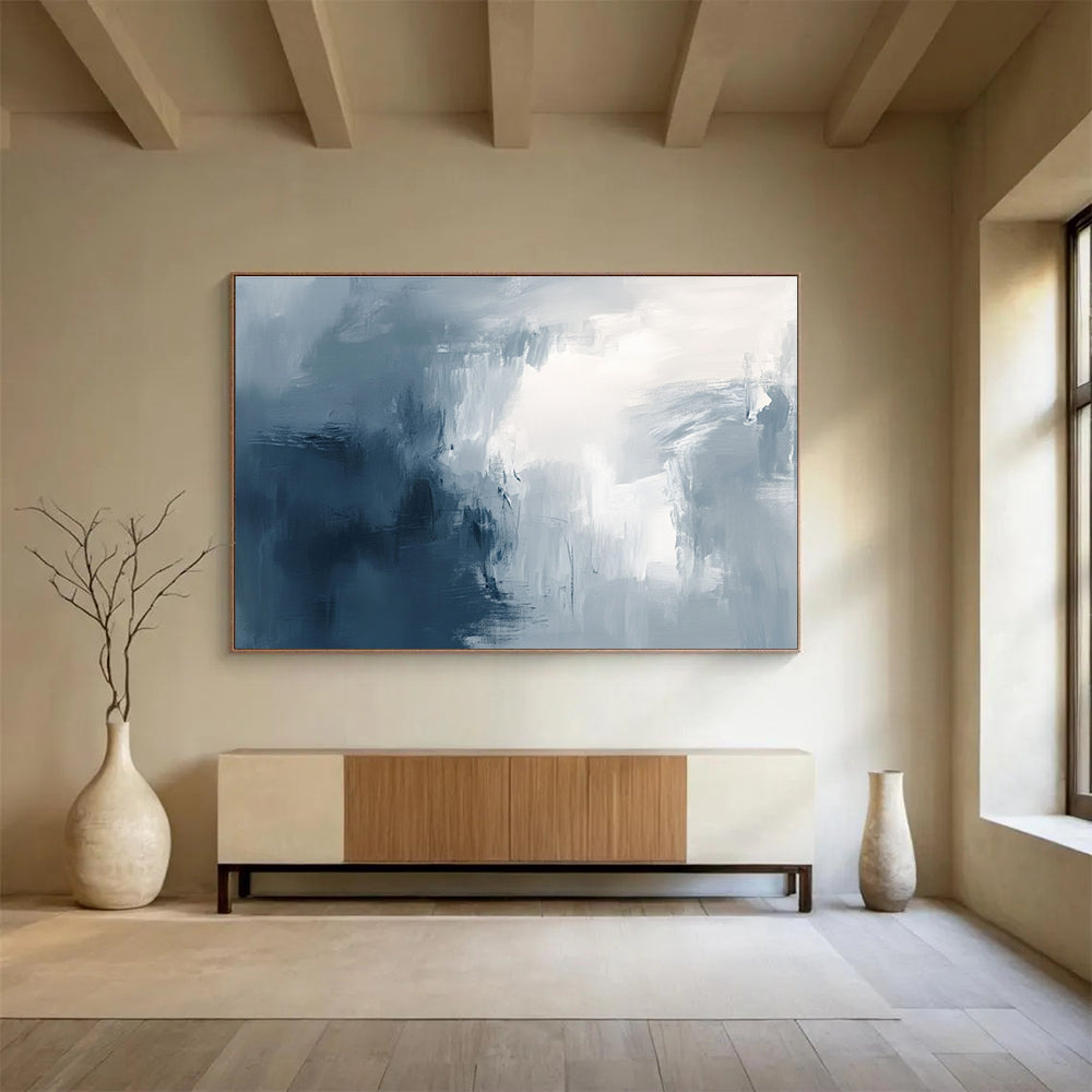 Large abstract painting with broad brush strokes in gray white and navy blue evoking calmness and introspection through soft gradients.SC048