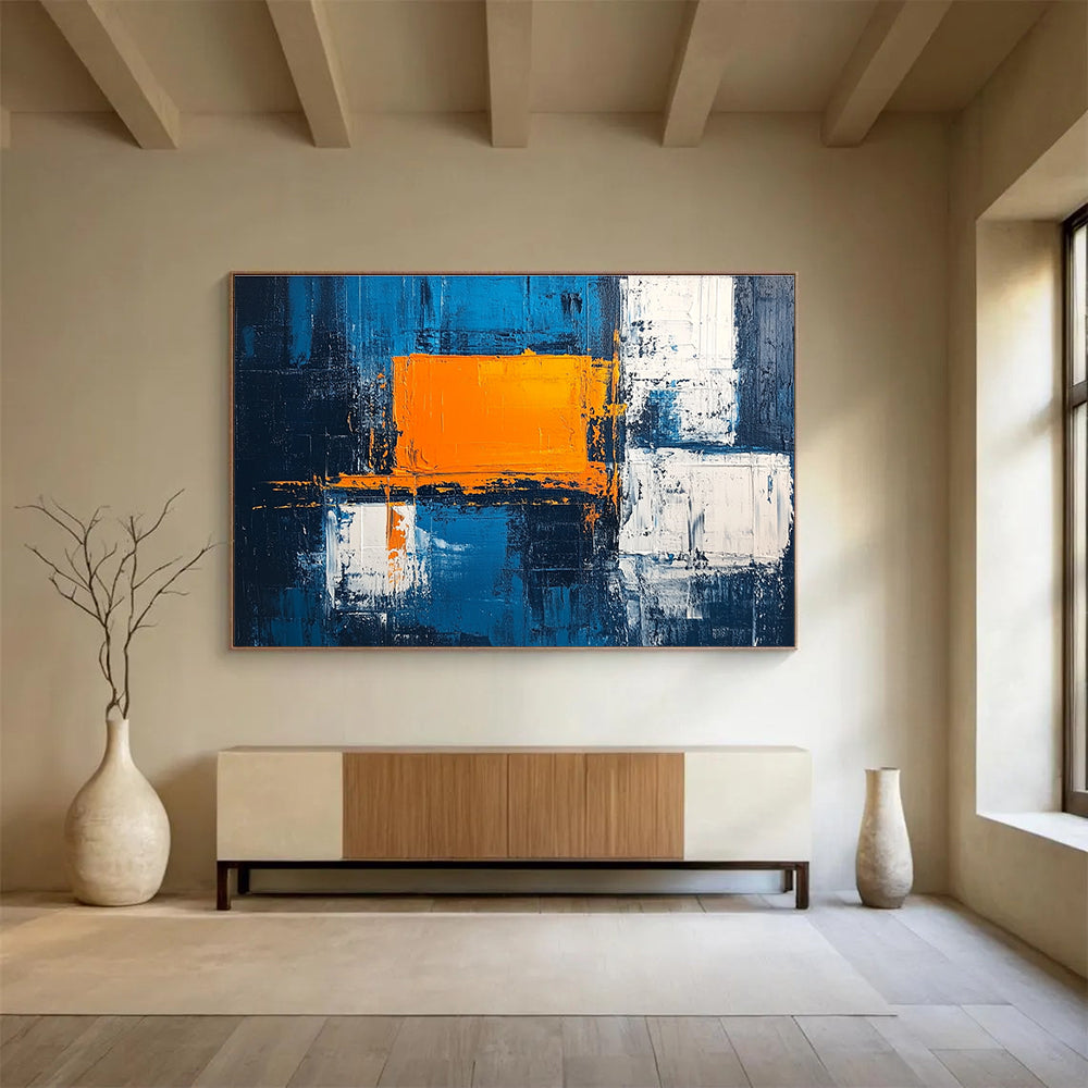 Large abstract painting featuring a textured pale blue background bold orange square white blocks and dark gray light indigo accents in acrylic.SC225