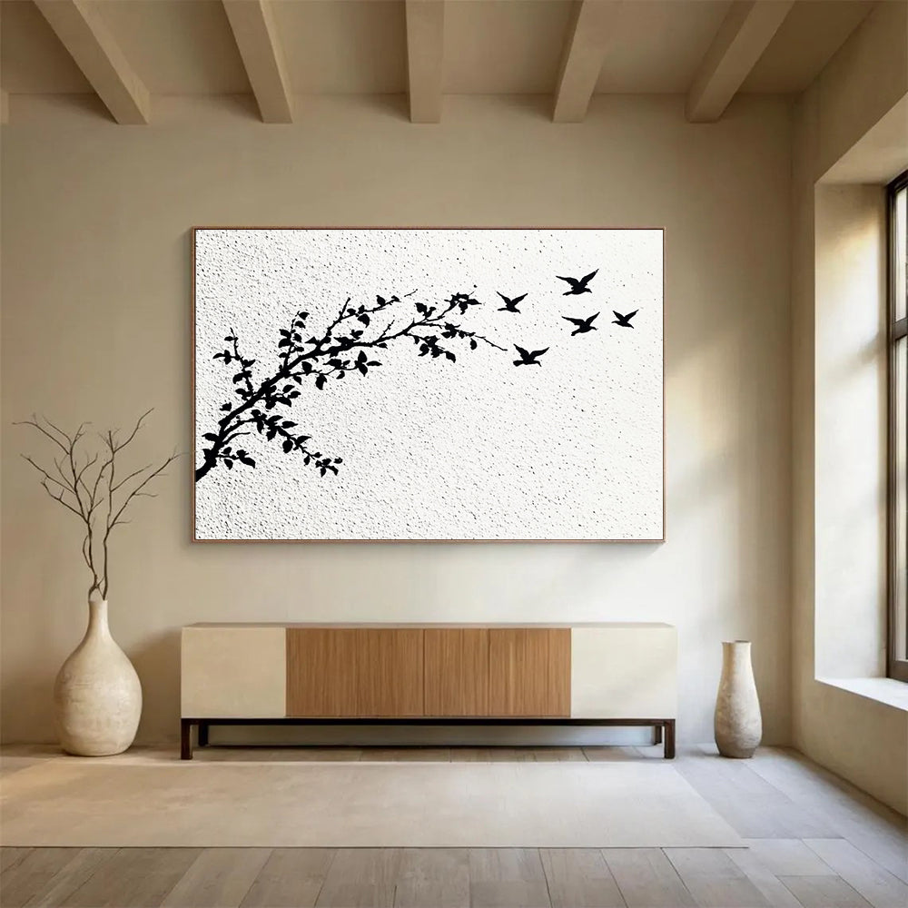 A large abstract painting featuring delicate branches with leaves and black and white flying birds against an off-white wall.SC434