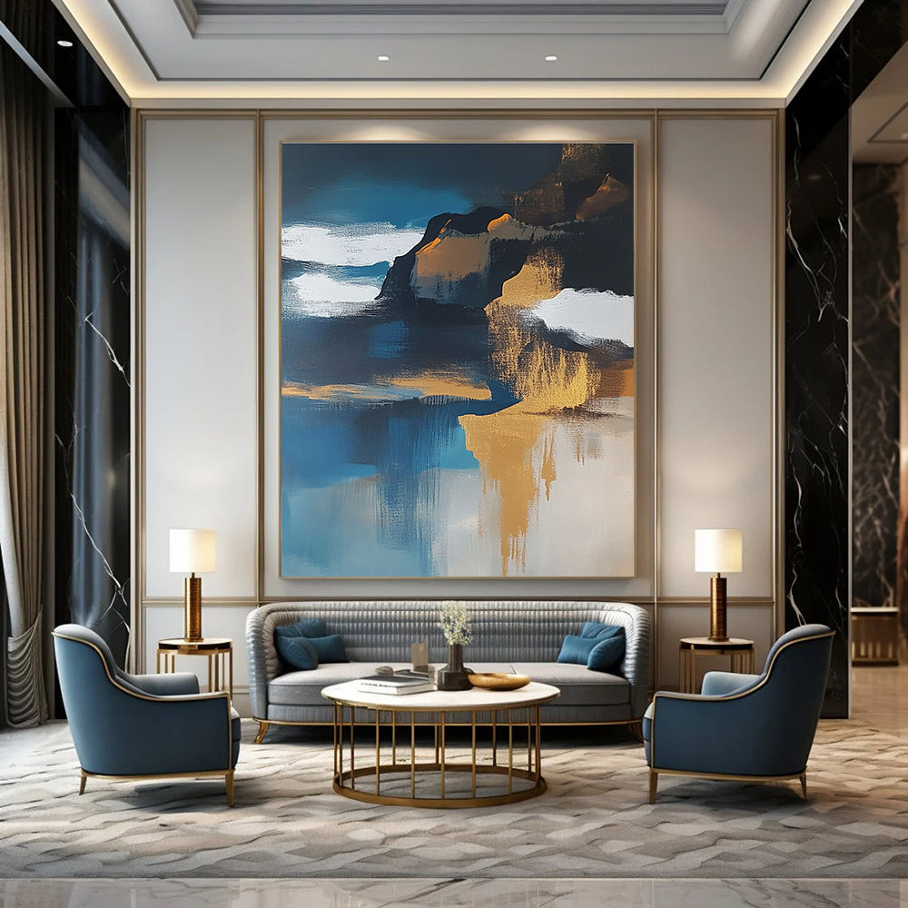 Large abstract painting of an island featuring navy blue water white clouds brown sand and gold leafing exuding a sense of calmness.STSC651