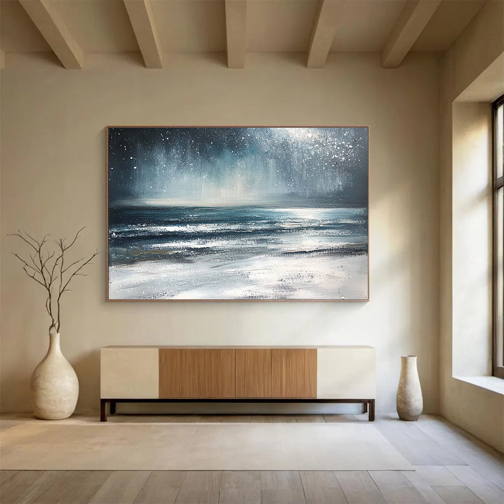 Large abstract painting depicting a winter ocean scene with dark blue and gray tones a starry white sky and sandy beach resembling snow.SC412