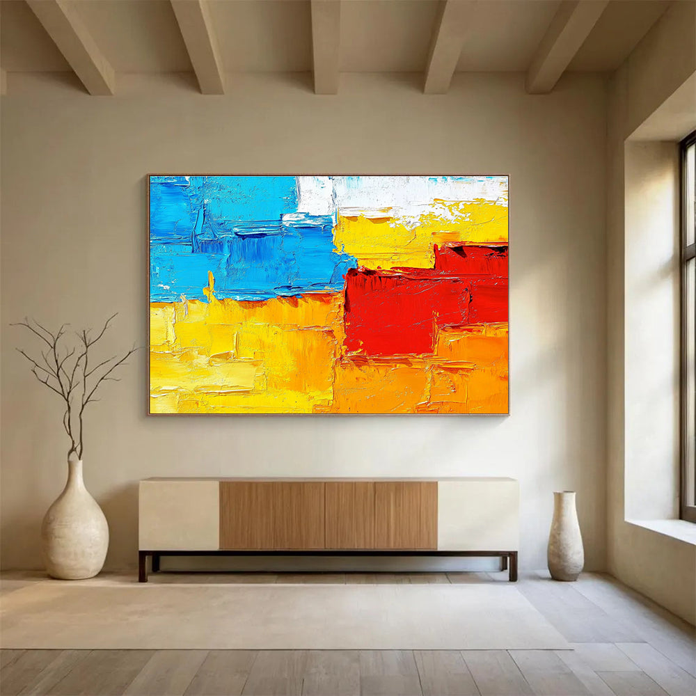 Large abstract painting featuring textured impasto brushstrokes in warm sunset tones of orange red yellow and blue.SC261