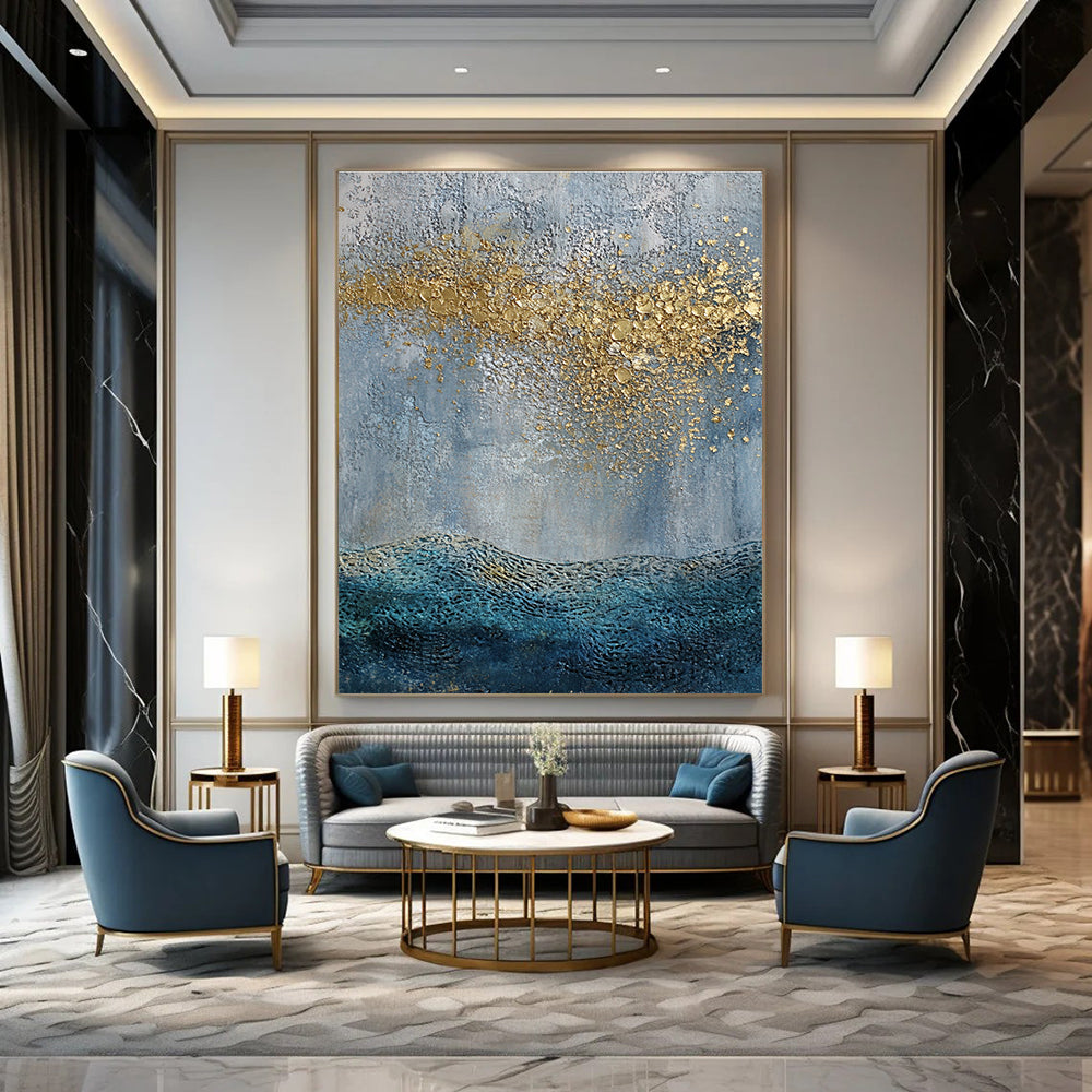 Large abstract painting with a textured sky-blue gray background and golden highlights featuring a textured sea with gentle waves in the foreground.STSC835