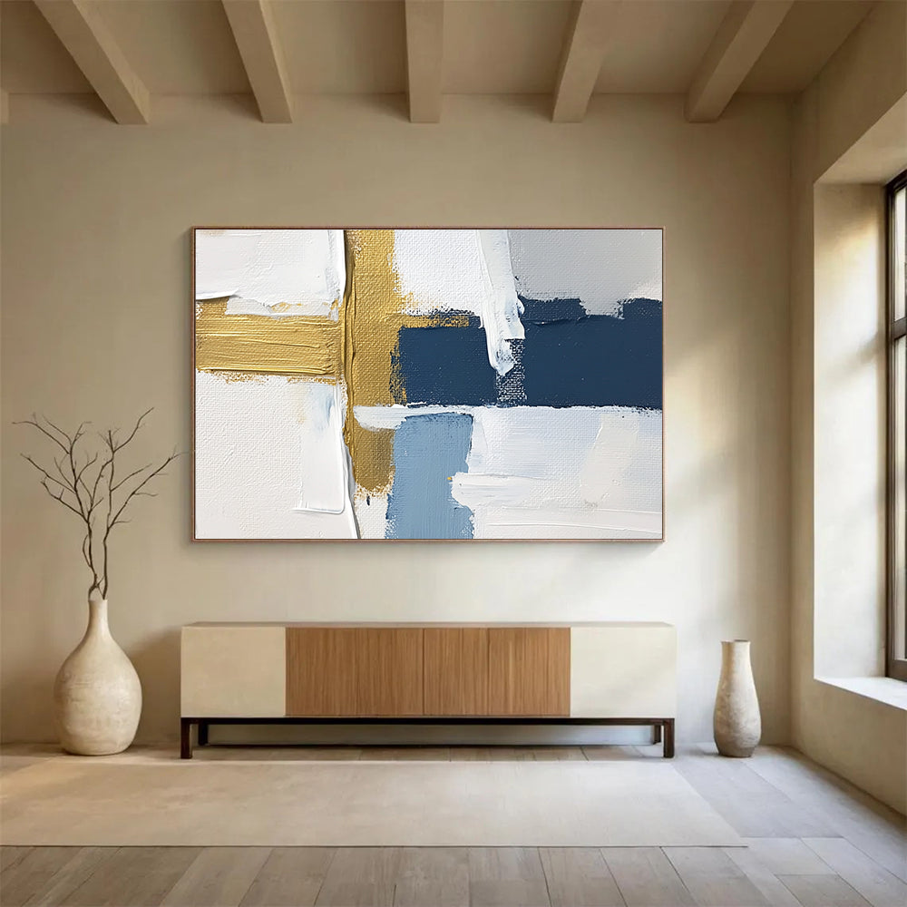 Large abstract painting with white blue and gold blocks featuring brushstrokes and texture showcasing a golden cross for depth in a serene atmosphere.SC267