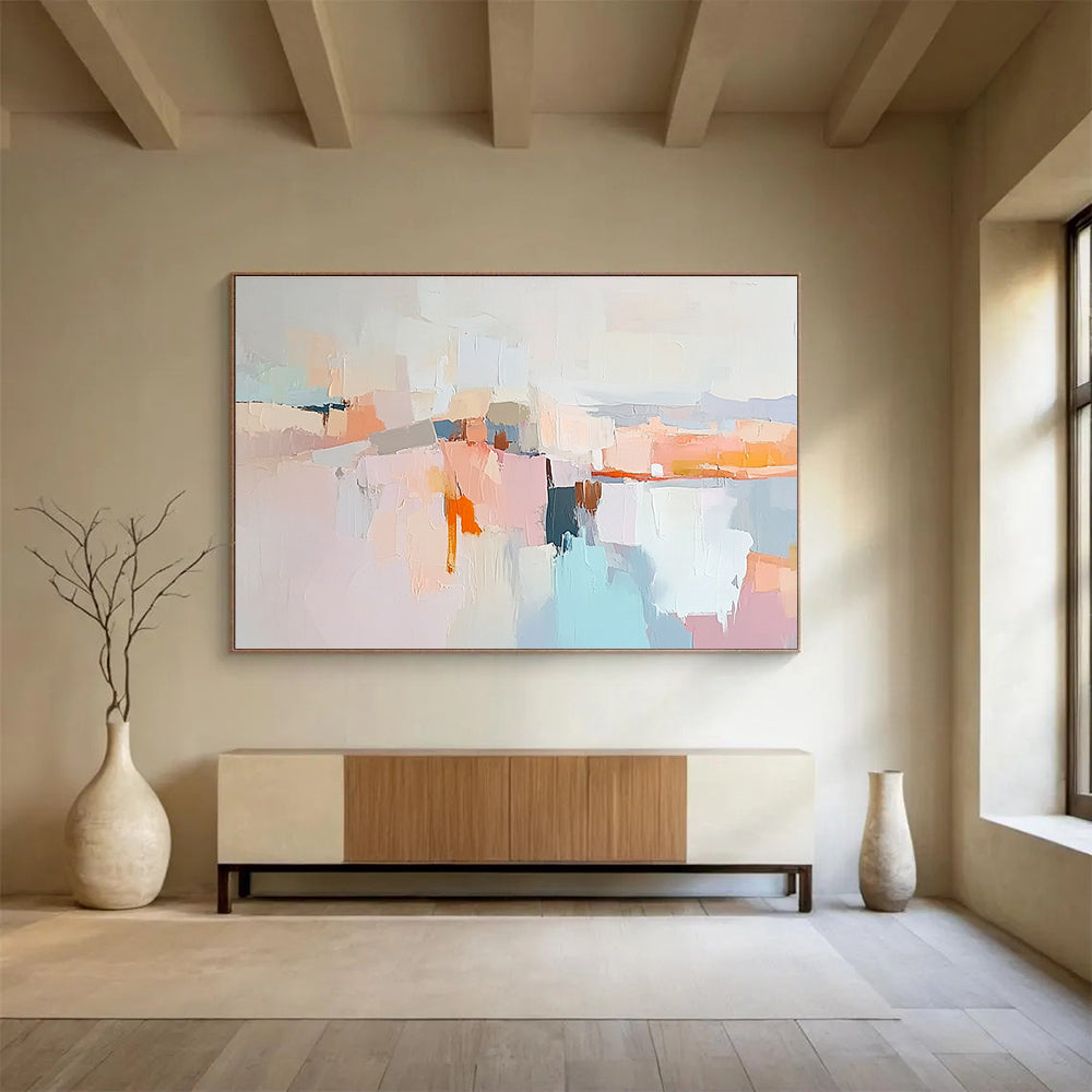 Large abstract painting in soft pastels featuring hills mountains a light grey sky peach-pink clouds and serene water for a calming effect.SC353